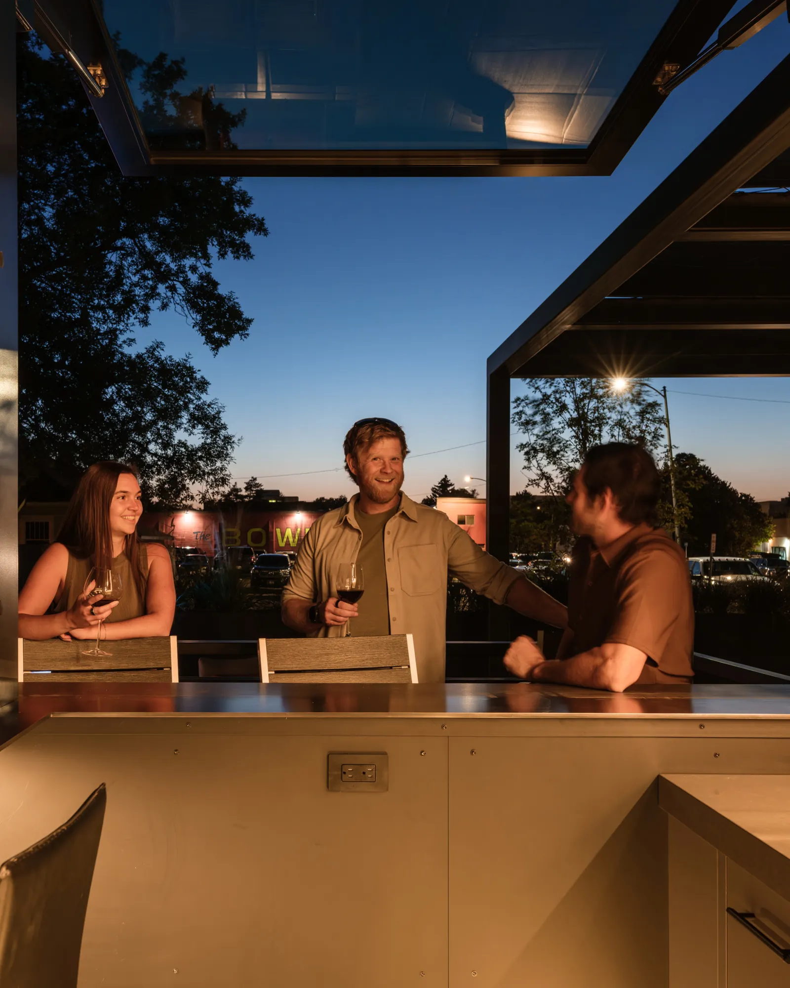 Guests talking over drinks in the glass-roofed sunroom at dusk